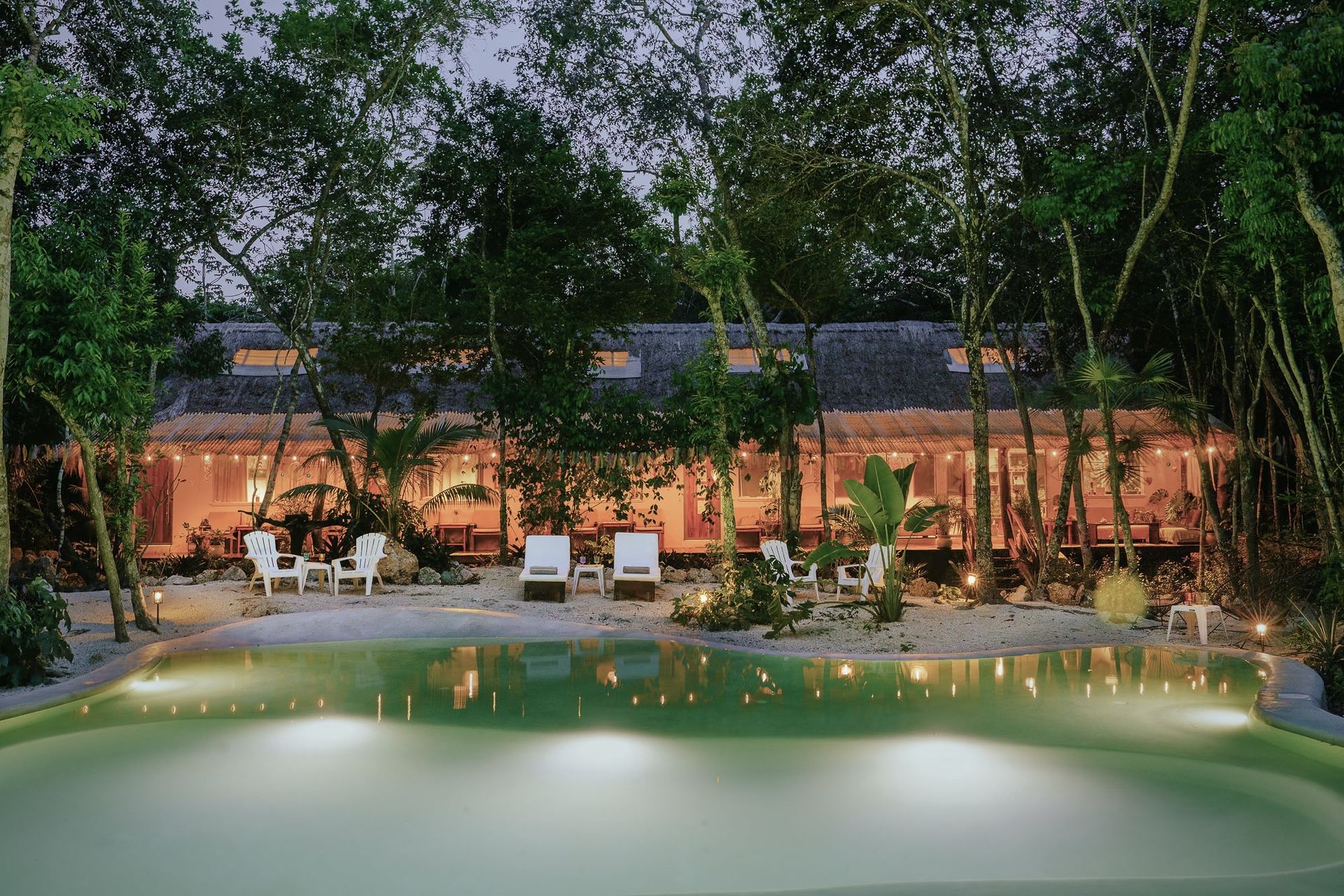 The cenote-fed pool at Casa Arkaana at dusk, surrounded by the Tulum jungle