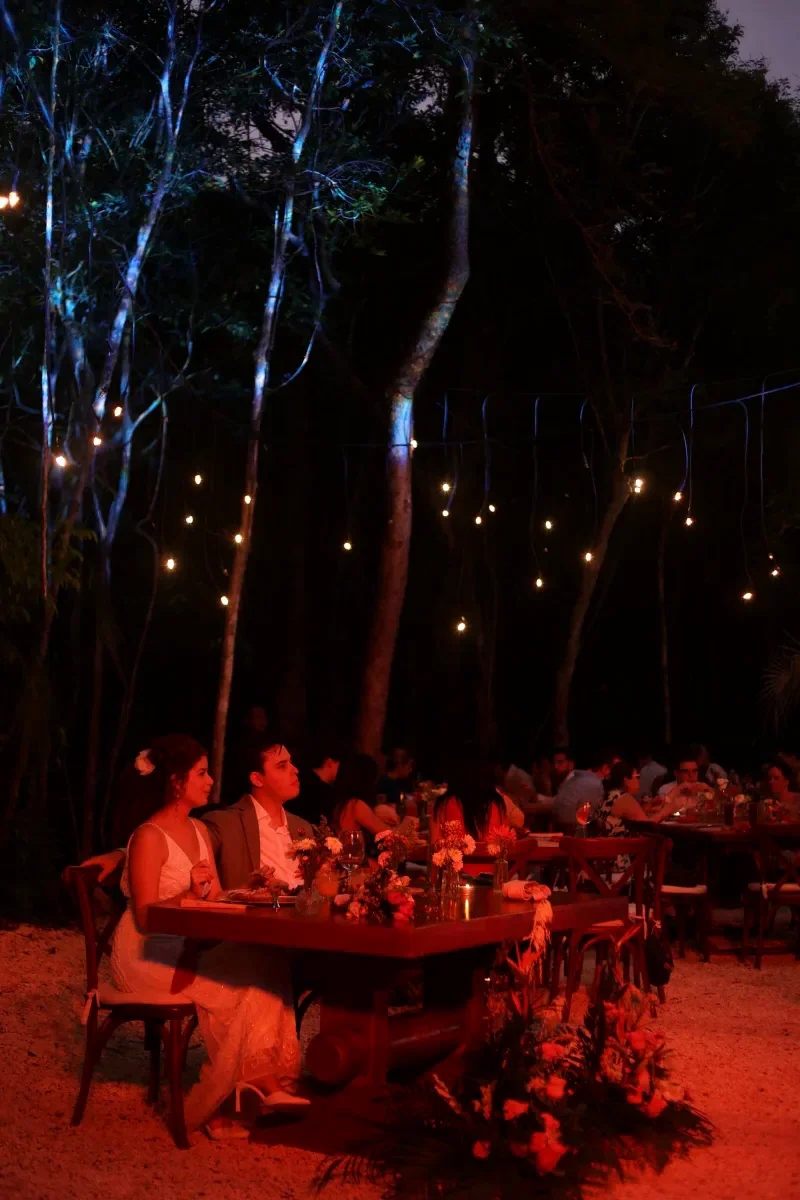 Luces de foquitos brillando sobre la cena de boda en la selva de noche